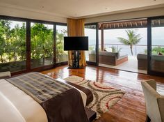 a bedroom with wooden floors and sliding glass doors leading to a balcony overlooking the ocean