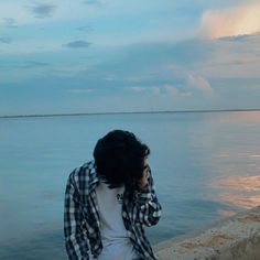 a person sitting on a ledge near the water