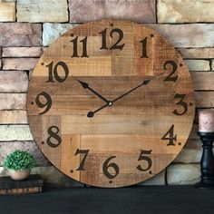 a wooden clock sitting on top of a mantle next to a candle and potted plant