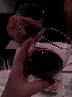 two people are holding wine glasses at a table