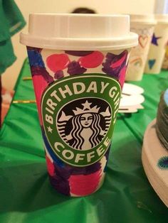 a starbucks cup sitting on top of a green table covered in colorful confetti