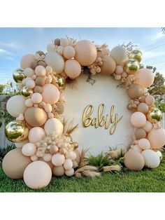 a baby shower with balloons and greenery in the shape of a circle on grass