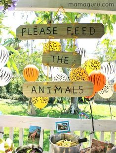 a wooden sign that says please feed the animals on top of a table filled with food