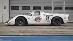 a white race car parked in front of a garage