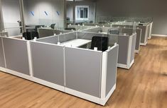 an office cubicle with glass partitions on the wall and wood flooring in front of it