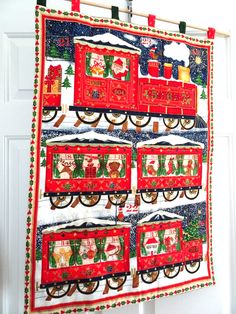 a christmas train quilt hanging on a door with santa's sleigh in the background