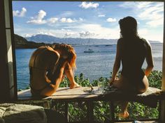 two women sitting on a porch looking out at the water