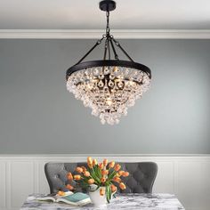 a chandelier hangs over a dining room table with tulips on it