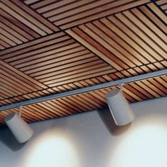 three spotlights are hanging from the ceiling in a room with wood slats on it