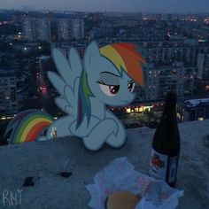 a bottle of beer sitting on top of a building next to a cut out of a rainbow