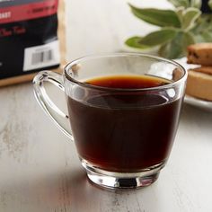 a cup of tea sitting on top of a table next to a bag of coffee