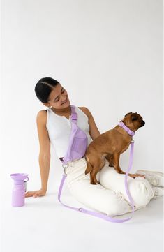 a woman is holding a dog while sitting on an inflatable pillow with a purple leash