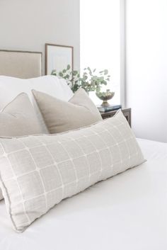 a bed with white sheets and pillows on top of it