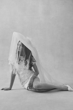 a black and white photo of a woman laying on the ground with a veil over her head