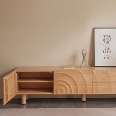 a wooden entertainment center with an art print on the wall next to it and a vase