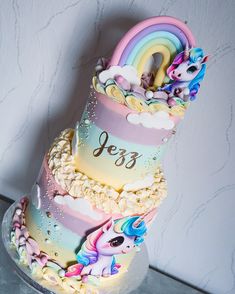 a three tiered cake decorated with rainbows and unicorns