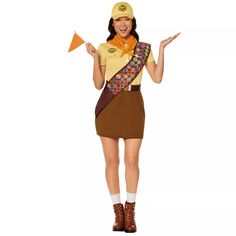 a woman dressed in a costume with a hat and scarf on her head is holding an orange paper airplane