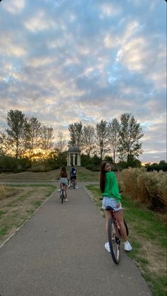 two girls riding bikes down a path in the park