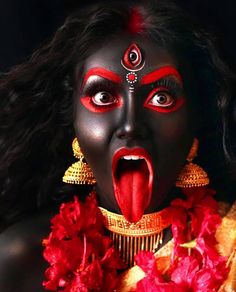 a woman with black face paint and red flowers around her neck is making a funny face