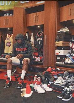 a man sitting in a locker with shoes on the floor and other items around him