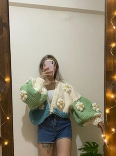 a woman taking a selfie in front of a mirror with flowers on her sweater