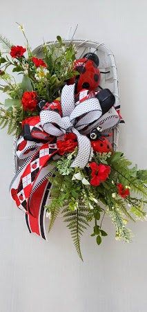 a red, white and black bow with flowers on it hanging from the side of a wall