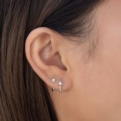 a close up of a woman's ear wearing two small white diamond studs