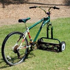 a bicycle is parked in the grass with a snow plow attached to it