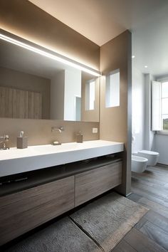 a bathroom with two sinks and a large mirror above the sink is lit by lights