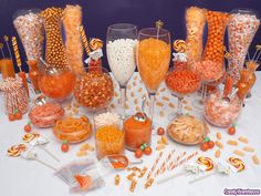 a table topped with lots of candy and candies next to glasses filled with liquid