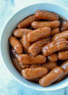 a white bowl filled with hot dogs on top of a blue tablecloth covered counter