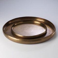 two round brass trays on a white surface