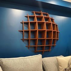 a room with blue walls and a wooden shelf on the wall behind a gray couch