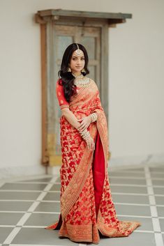 a woman in an orange and red sari is posing for the camera with her hands on her hips