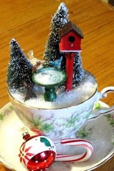 a teacup with christmas decorations on it and a birdhouse in the cup next to it