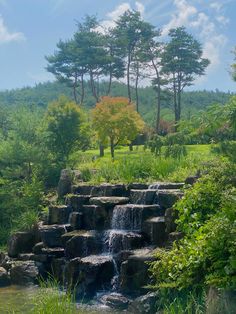 a small waterfall in the middle of a lush green field