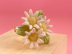 a close up of a ring with flowers on it sitting on top of a wooden block