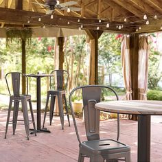 an outdoor dining area with tables and stools under a wooden pergolated roof