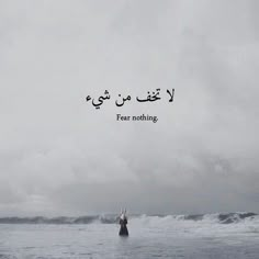 a person standing in the ocean with an arabic quote above them that reads fear nothing