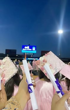 several women in pink dresses and hats holding up toothbrushes