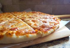 a cheese pizza sitting on top of a wooden cutting board next to a spatula