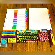 an assortment of school supplies laid out on a wooden table, including notebooks and markers