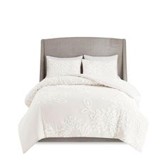 a bed with white comforter and pillows on it's headboard, in front of a white background