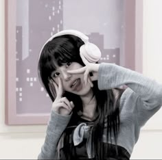 a woman with headphones on her ears posing for a photo in front of a cityscape