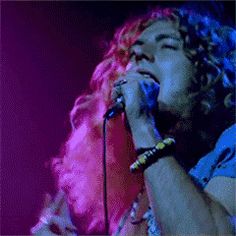 a man with curly hair singing into a microphone