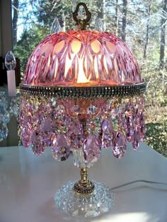 a pink chandelier sitting on top of a white table next to a window