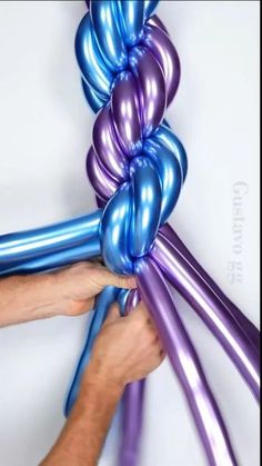 a person is holding some balloons in their hand and they are blue and purple with one balloon attached to the other