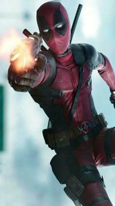 the deadpool character is holding a fireball in his right hand and pointing at it