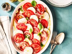 a bowl filled with sliced tomatoes and mozzarella cheese on top of a blue table