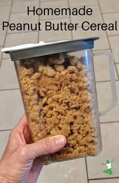 a person holding up a container full of peanut butter cereal in front of the words homemade peanut butter cereal